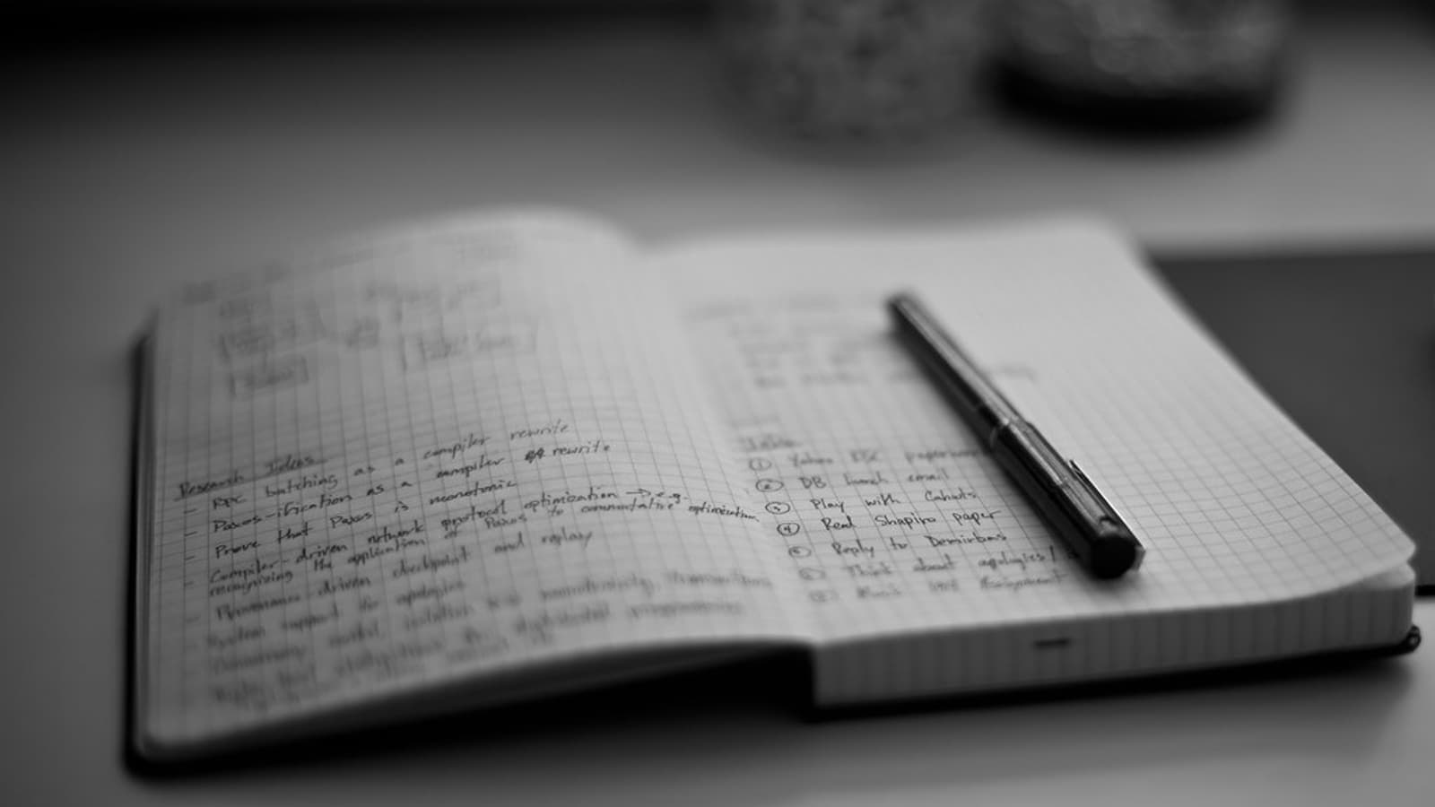 A notebook, pen and wrapped parcel on a pale desk