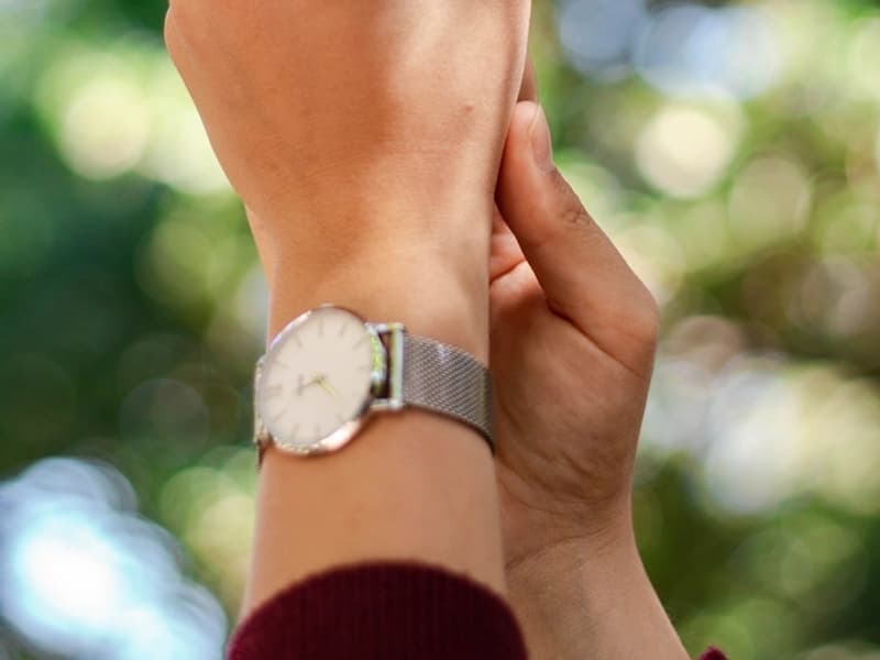 A steel wristwatch on a pale surface
