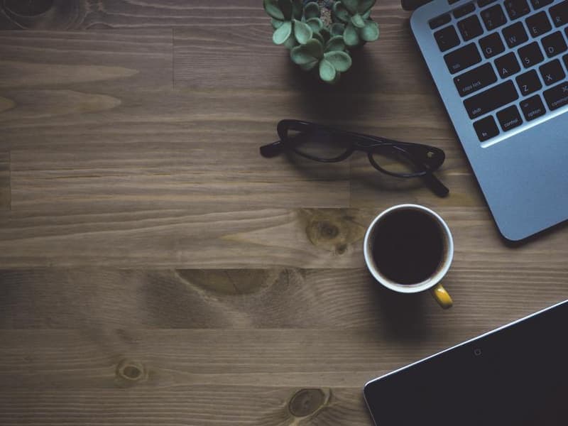 A ceramic mug on a desk beside a notebook
